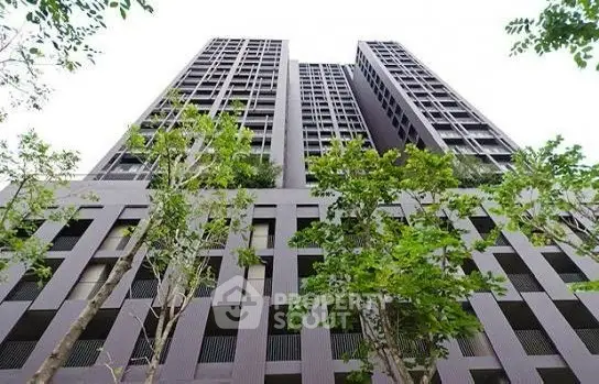 Modern high-rise building with lush greenery and sleek architectural design.