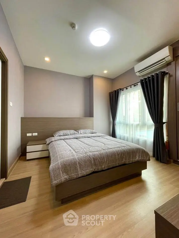Modern bedroom with cozy decor, featuring a double bed, wooden flooring, and natural light from large windows.