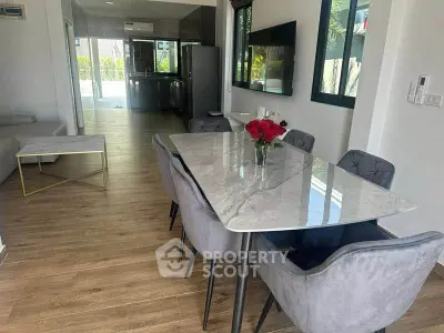 Modern dining area with elegant marble table and plush chairs in open-plan living space.
