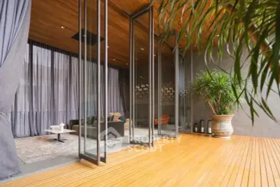 Luxurious modern living room with floor-to-ceiling glass doors opening to a stylish wooden deck.