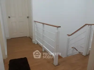 Modern staircase with wooden flooring and sleek railing in a contemporary home.