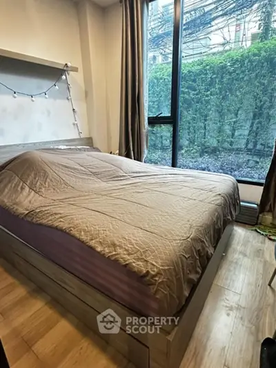 Cozy bedroom with large window and garden view, featuring a comfortable bed and stylish decor.