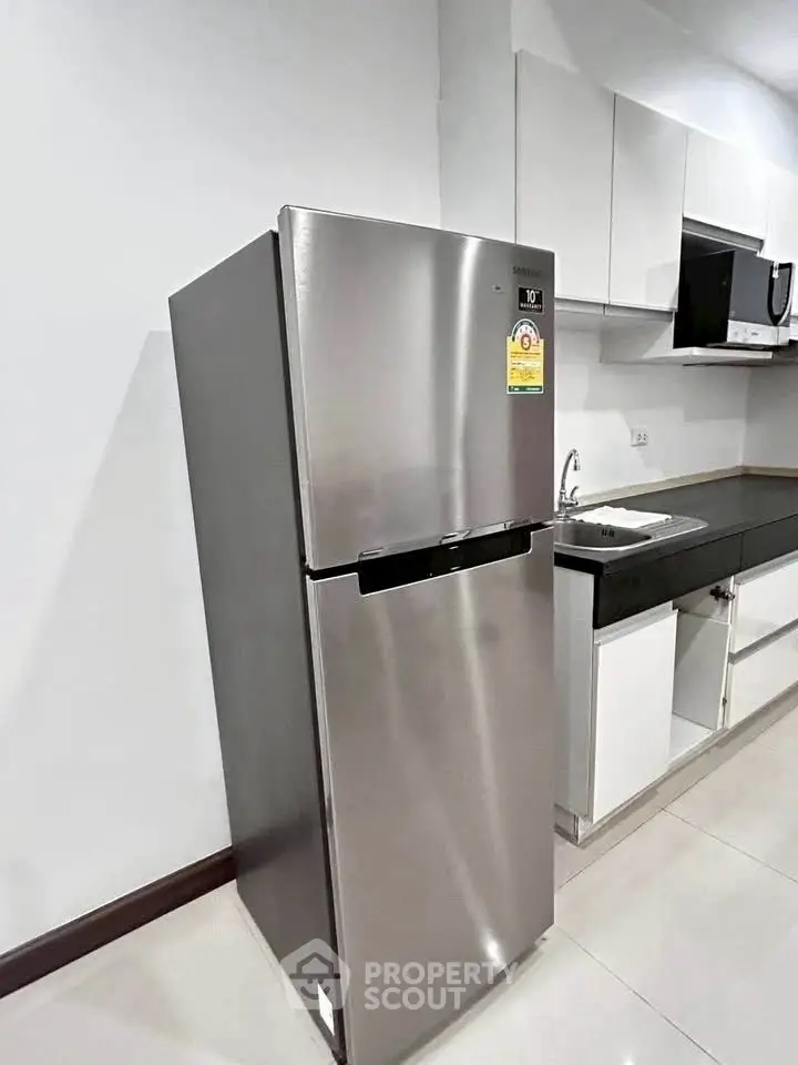 Modern kitchen with sleek stainless steel fridge and minimalist design.