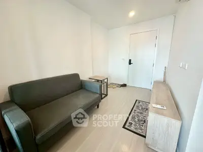Modern minimalist living room with sleek black sofa and light wood flooring.