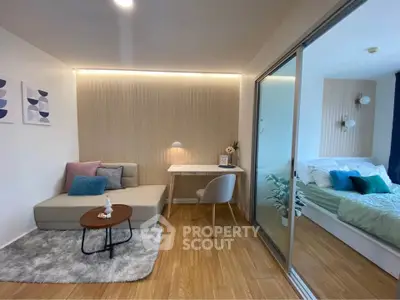 Modern studio apartment with cozy living area and stylish bedroom separated by glass partition.