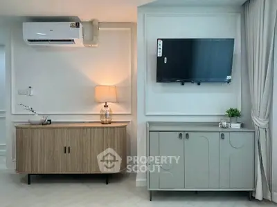 Modern living room with stylish furniture and wall-mounted TV, featuring elegant lighting and air conditioning.