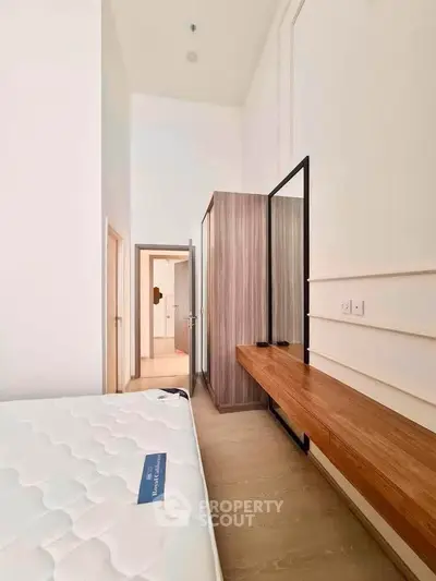 Modern bedroom with minimalist design, featuring a wooden wardrobe and sleek furniture.