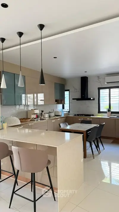 Modern kitchen with sleek design, featuring an island, stylish pendant lights, and contemporary appliances.