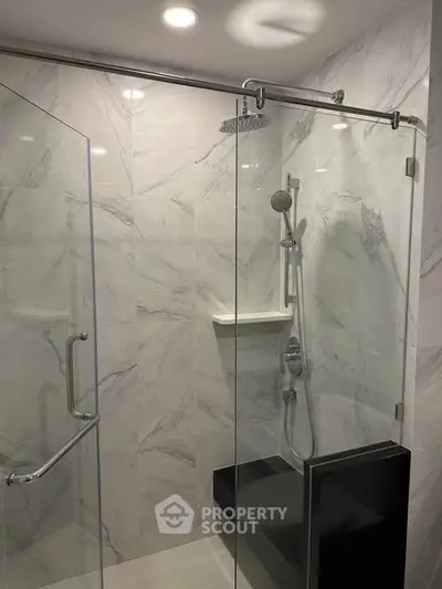 Luxurious modern bathroom with glass shower enclosure and elegant marble tiles.