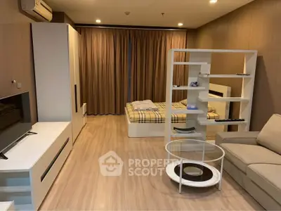 Modern studio apartment with integrated living and sleeping area, featuring sleek furniture, wooden flooring, and warm ambient lighting.