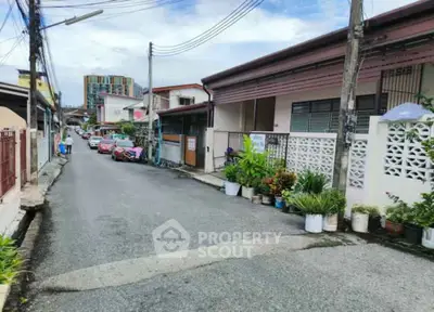 Charming residential street with cozy homes and lush potted plants, perfect for tranquil living.