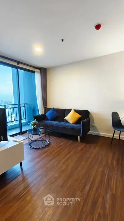 Modern living room with wooden flooring and balcony view in high-rise apartment.