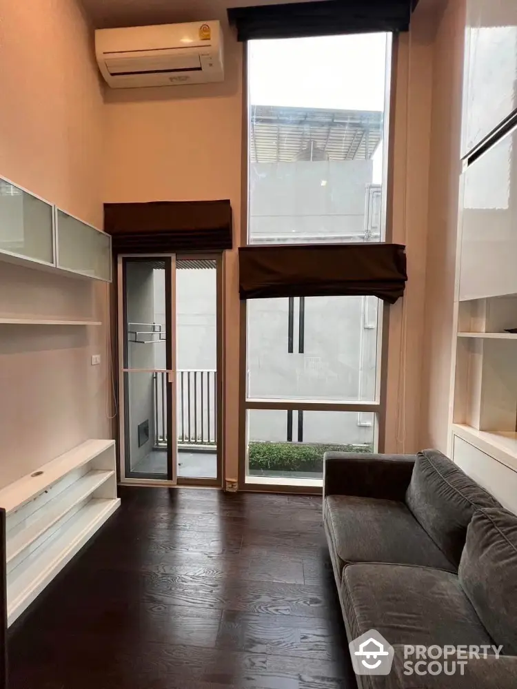 Modern living room with high ceilings and large windows in a stylish apartment.