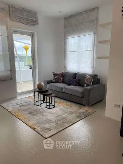 Chic living room with modern gray sofa, stylish rug, and access to a bright balcony.