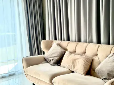 Elegant living room with plush beige sofa and floor-to-ceiling curtains, exuding luxury and comfort.