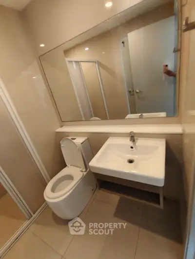 Modern bathroom with sleek fixtures and large mirror in a contemporary apartment.