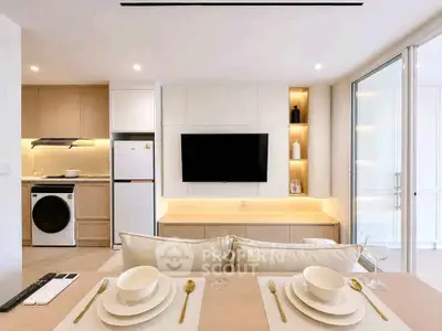 Modern open-plan living room with stylish kitchen and dining area, featuring sleek appliances and elegant decor.