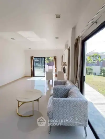 Spacious living room with elegant furniture and large windows offering garden views.