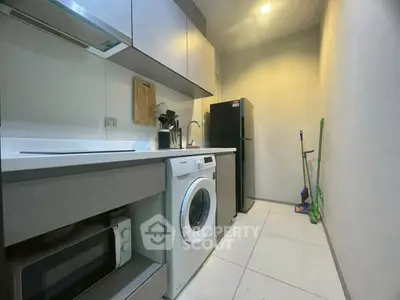 Modern kitchen with washing machine and sleek appliances in compact layout