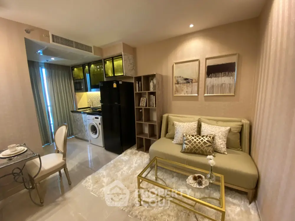 Modern living room with stylish decor and compact kitchen featuring washing machine and fridge.