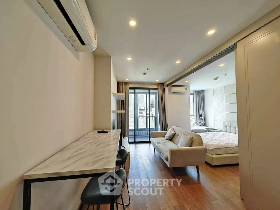 Modern open-plan living room with stylish furniture and balcony view in a contemporary apartment.