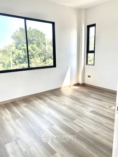 Bright empty room with large windows and wood flooring, perfect for customization.