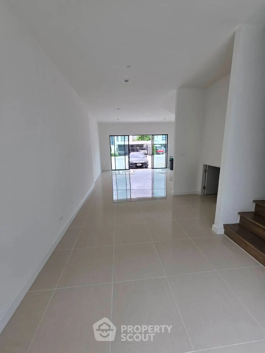 Spacious modern living room with large windows and glossy tiled floors
