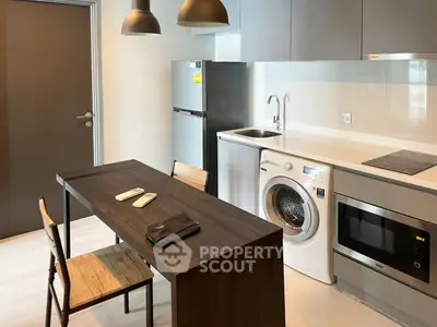 Modern kitchen with washing machine, fridge, and dining table in stylish apartment.