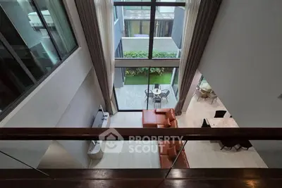 Stunning modern living room with high ceilings and garden view, featuring elegant furniture and floor-to-ceiling windows.