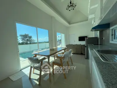 Spacious open-plan living area with pool view and modern kitchen