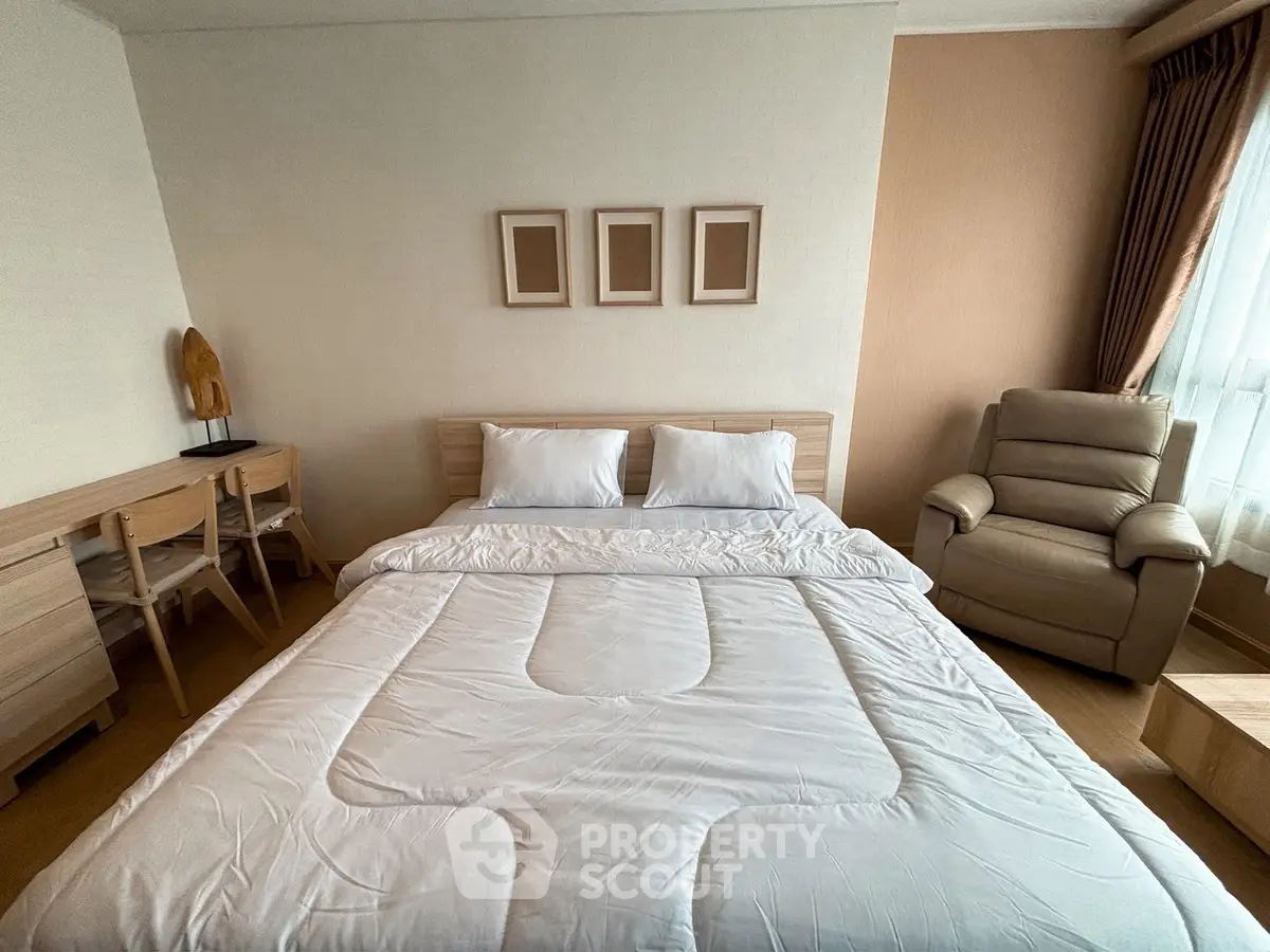 Cozy bedroom with stylish decor and natural light, featuring a comfortable bed and seating area.