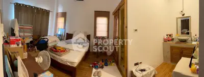 Cozy bedroom with wooden flooring and ample natural light, featuring a comfortable bed and organized storage.