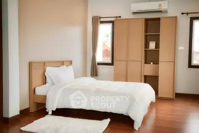 Cozy bedroom with wooden flooring and modern furnishings, featuring a single bed and built-in wardrobe.