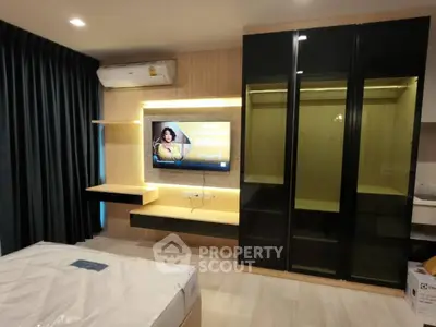 Modern bedroom with sleek wardrobe and mounted TV, featuring elegant lighting.