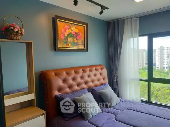 Charming bedroom with plush headboard and scenic window view in modern apartment.