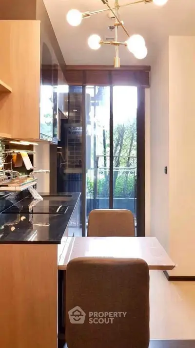Modern kitchen with sleek design and balcony view, featuring elegant lighting and compact dining area.