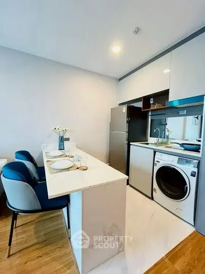 Modern kitchen with sleek appliances and stylish dining area in a compact layout.