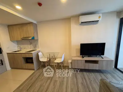 Modern living room with open kitchen, featuring sleek furniture and wood flooring.