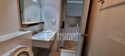 Modern bathroom with sleek fixtures and view into compact kitchen area.