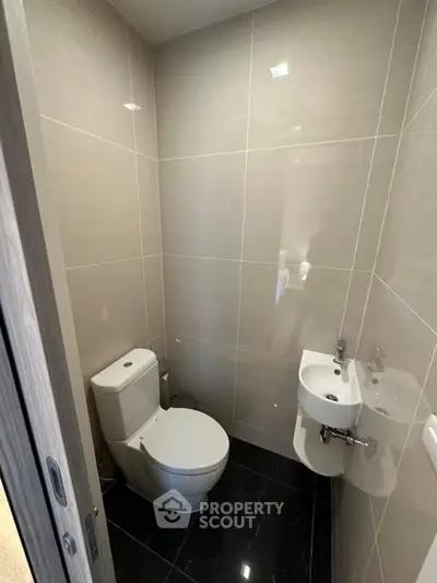 Compact modern bathroom with sleek fixtures and glossy tiles.
