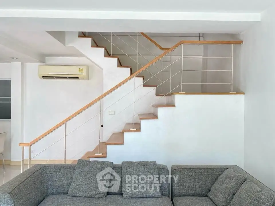 Modern living room with sleek staircase and air conditioning unit, perfect for contemporary living.