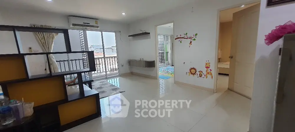 Spacious living area with balcony access and playful wall decor in modern apartment