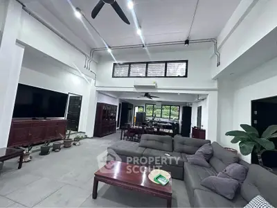Spacious living room with modern furniture and high ceiling, perfect for family gatherings.