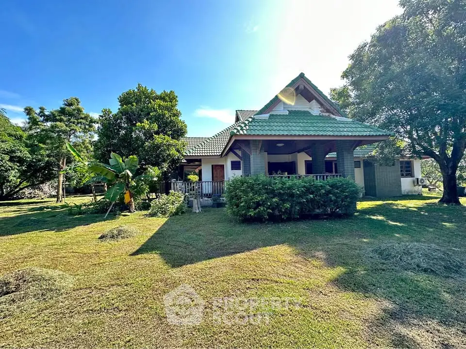 Charming countryside house with lush garden and spacious lawn under clear blue sky.