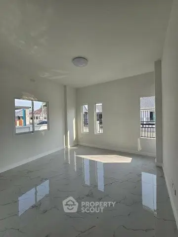 Spacious sunlit room with modern marble flooring and large windows in a contemporary home.