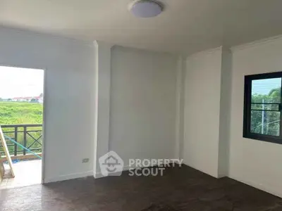 Spacious empty room with large window and balcony access, ideal for customization.