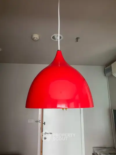 Modern interior with vibrant red pendant light and sleek white door, showcasing contemporary design.