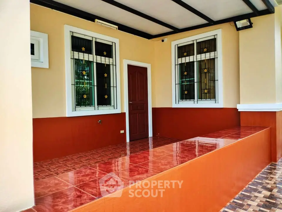 Charming entrance with tiled flooring and decorative window grills in a cozy home.