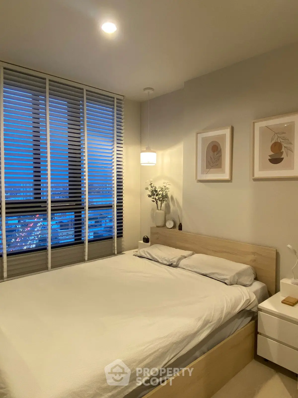 Cozy modern bedroom with city view, featuring minimalist decor and large window.