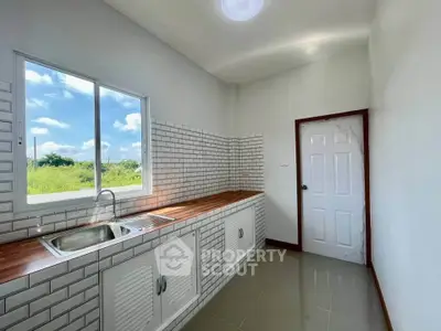 Modern kitchen with white brick backsplash and wooden countertop, featuring a large window with scenic view.